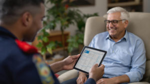 Paramedic using HealthCall platform on a tablet sitting across from a smiling man